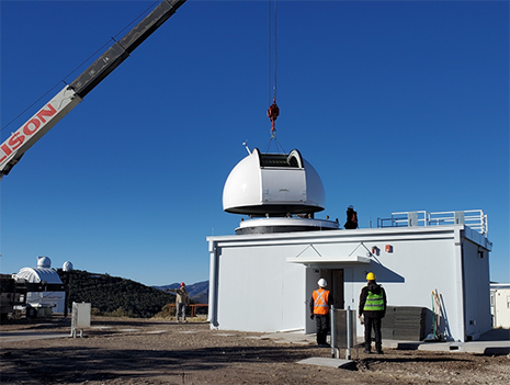 Lift of the dome onto the dome ring.  The McDonald Observatory 82-inch and 107-inch telescope facilities can be seen on top of Mt Locke in the background to the left in the picture.