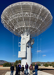 side view of the new VLBI antenna with people atanding in front of it.