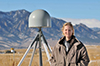 Dr. Kristine Larson stands next to aGPS receiver in Boulder, Colorado, USA